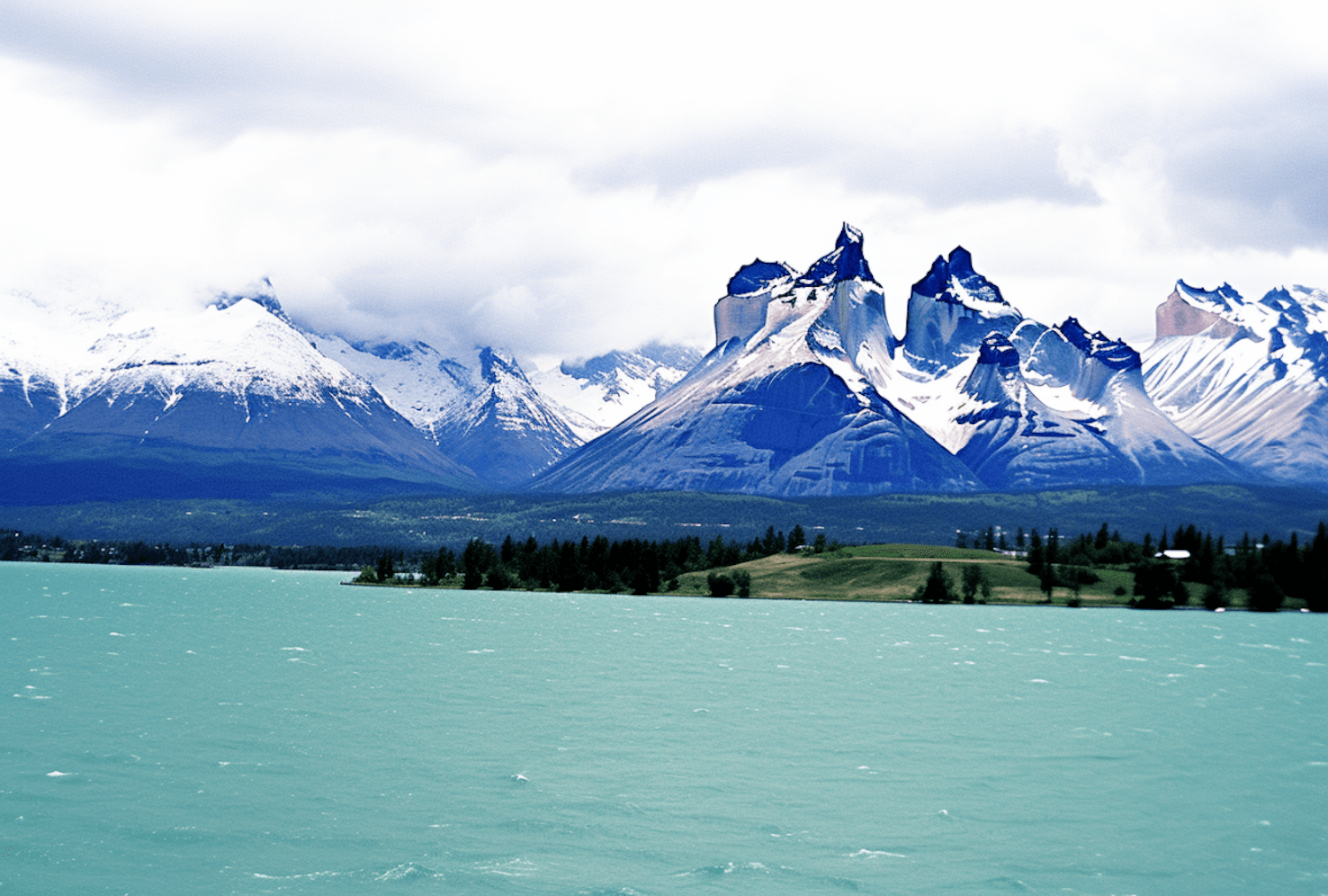 Snow-capped mountains rising above a turquoise alpine lake